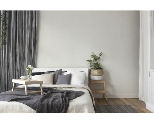 Ljust sovrum med säng, sängbord, växt och gardiner