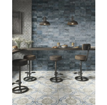 Köksscen med blå väggplattor, mönstrade golvplattor och barstolar.