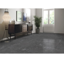 Vardagsrum med mörka golvplattor, byrå, golvlampa och krukväxt