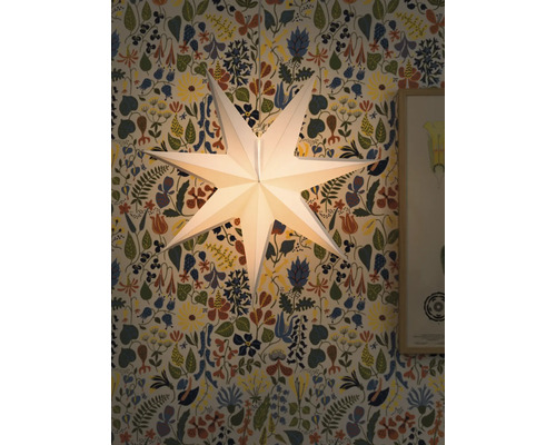 Lysande pappersstjärna som dekoration framför en blommig tapet