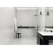 Ljust badrum med mosaikplattor på väggarna, dusch och handfat.