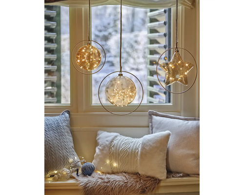 Dekorativa hänglampor i form av en sfär och en stjärna med ljusslingor framför ett fönster