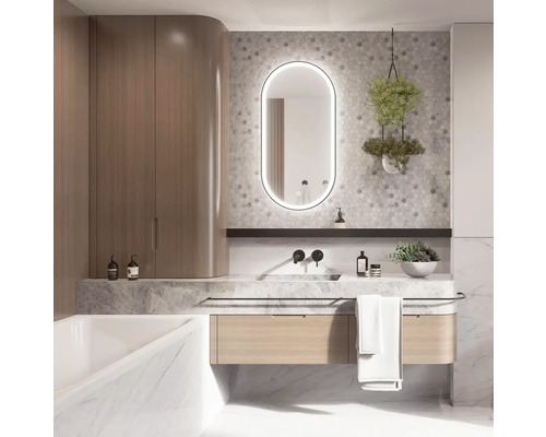 Badrum med tvättställ, belyst spegel, hängande växt och badkar