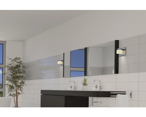 Ljust badrum med handfat, spegel, vägglampor och växter