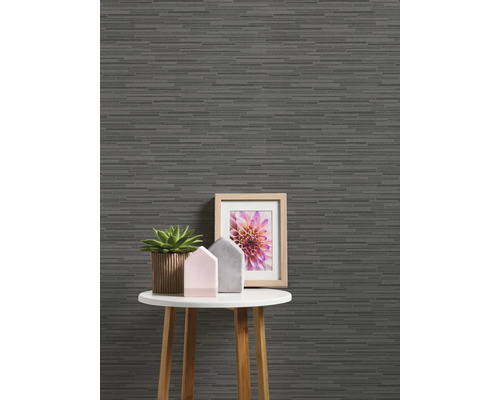 Dekorativ tapet med horisontellt randmönster på en vägg bakom ett litet bord med dekorationer