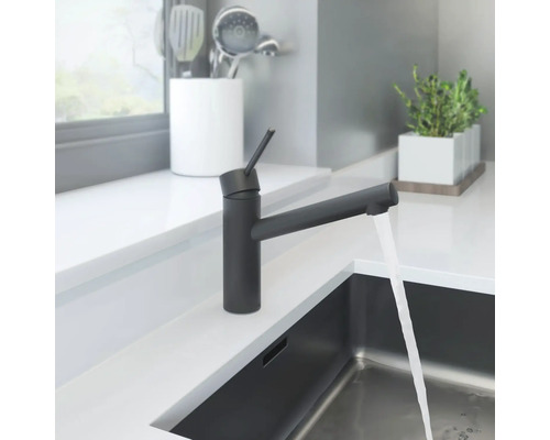 Svart köksblandare med rinnande vatten i modern köksdesign.