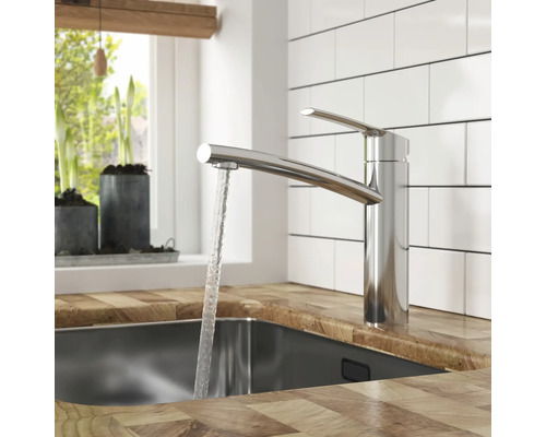 Köksscen med en metallkran och rinnande vatten i en diskho