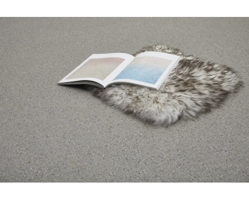 Öppen bok ligger på en fällmatta på ett golv.