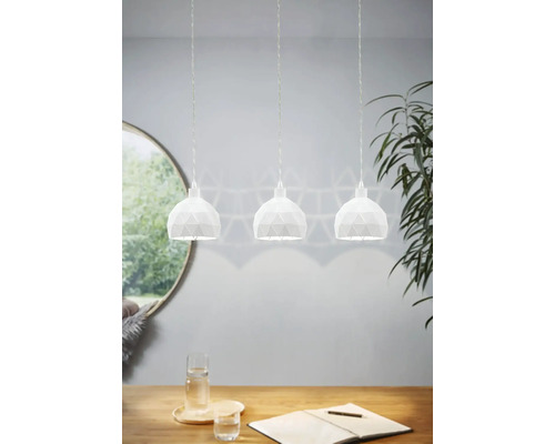 Tre vita hänglampor med geometrisk design över ett träbord