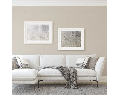 Vardagsrum med soffa, kuddar och inramade bilder på väggen