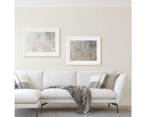 Vardagsrum med soffa, kuddar, filt och två inramade konsttryck