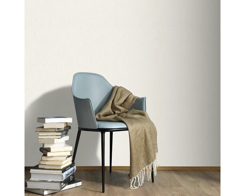 Ljust rum med bokstapel, stol och filt