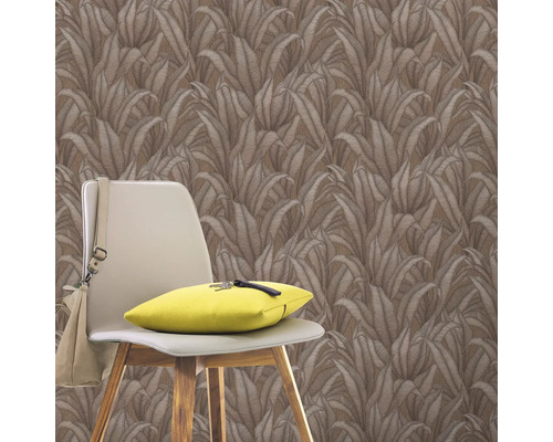 Vägg med tapet med bladmönster, stol med kudde och väska