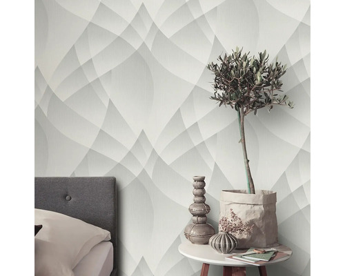Miljöbild med geometrisk tapet, säng och bord med dekorationer.