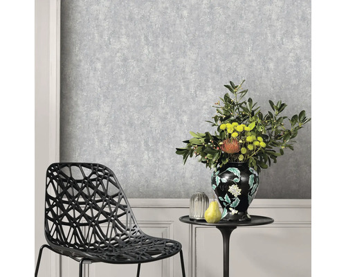 Miljöbild med en grå strukturtapet, en stol och ett bord med en blomvas