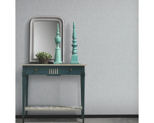 Dekorativ interiör med bord, spegel och ornament framför en vägg med tapet