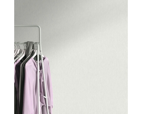 Ljus väggtapet med textilmönster bredvid en klädställning