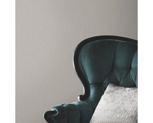 Närbild av en strukturtapet med en fåtölj i bakgrunden.