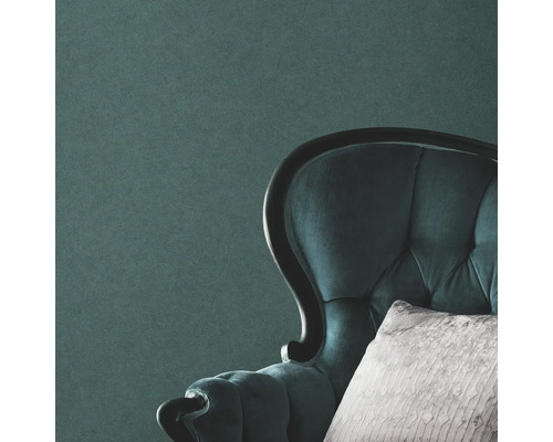 Närbild av en vadderad fåtölj med kudde framför en vägg