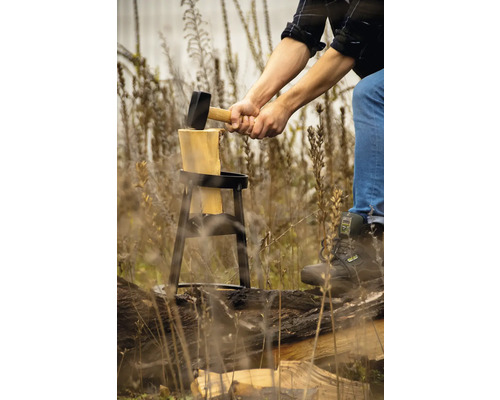Man hugger ved med en klyvhammare på en huggkubbe