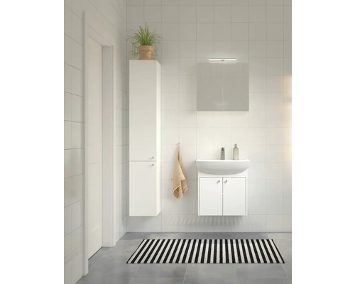 Badrum med handfat, spegelskåp, högskåp och svartvit randig matta