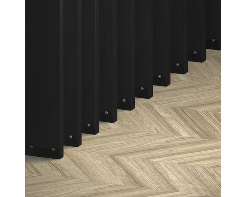 Detaljvy av svarta stängselelement på ett ljust fiskbensparkettgolv