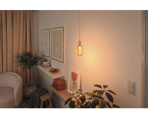 Vardagsrum med hängande lampa och dekoration på väggen