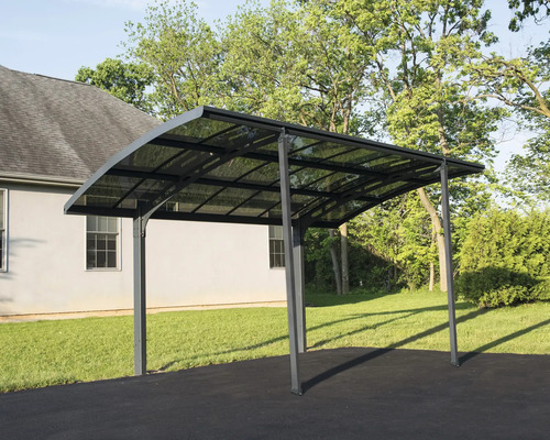 Fristående carport i metall med transparent tak framför ett hus.