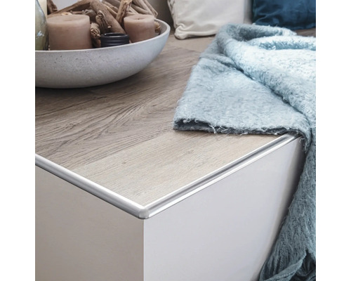 Aluminiumkantlist på en vit byrå med trägolv