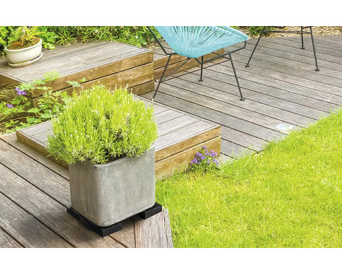 Utomhusmiljö med träterrass, växt i kruka på växtrullar och trädgårdsmöbler.