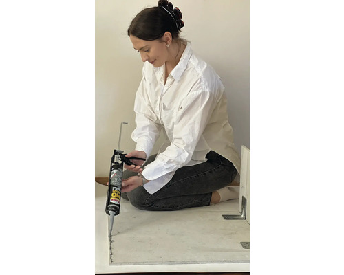 En kvinna använder en fogpistol för att foga.