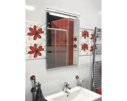 Ljust badrum med handfat, belyst spegelskåp och blommiga kakelplattor