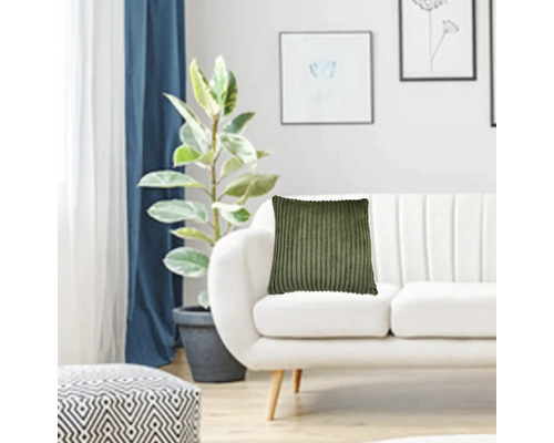 Dekorativt vardagsrum med soffa, krukväxt och manchesterkudde.