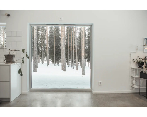 Ljust rum med utsikt över en snötäckt skog genom ett stort fönster