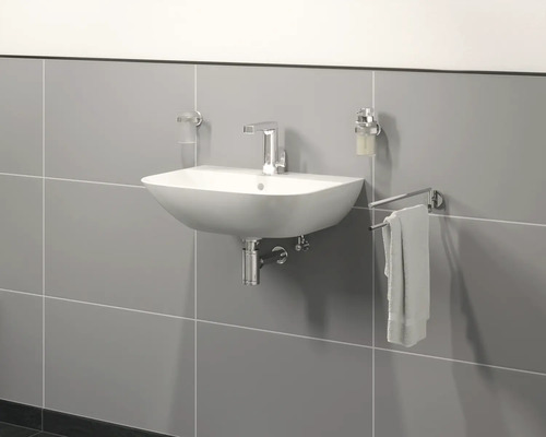 Handfat med armatur, tvålpump, tandborstmugg och handdukshållare på grå vägg