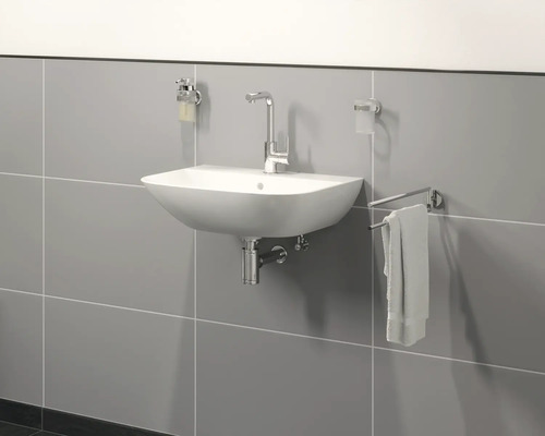 Badrum handfat med blandare, tvåldispenser, tandborstmugghållare och handdukshängare på en kakelvägg