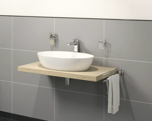 Tvättställ på träskiva med armatur, tvålpump, tandborstmugg och handdukshållare framför en grå vägg