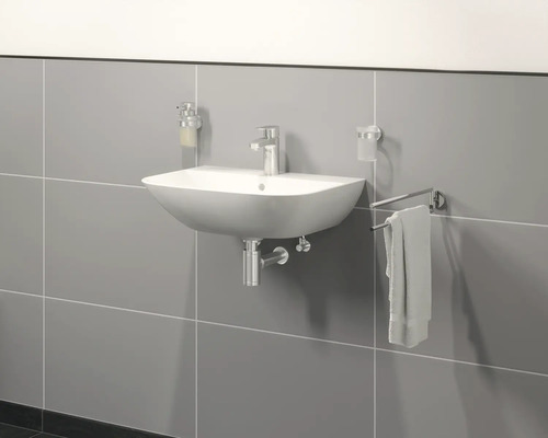 Vägghängd tvättställ med armatur, tvålpump, tandborstmugg och handdukshållare på grå vägg