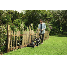 Man klipper gräs med en gräsklippare i en trädgård