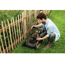 Man byter batteri på en gräsklippare i trädgården.