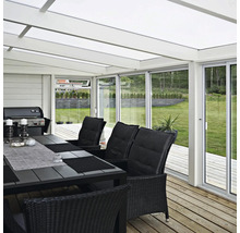 Ljus veranda med matbord, stolar, grill och utsikt över trädgården