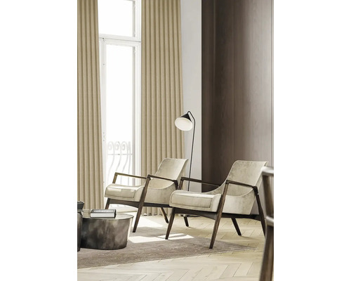 Vardagsrum med två fåtöljer och en golvlampa bredvid ett fönster med gardiner.