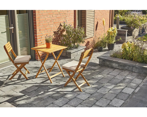 Trädgårdsscen med träbord och två stolar på trottoar framför ett hus