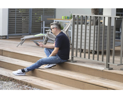 Man sitter på träterrass och använder en smartphone