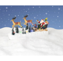 Jultomten med rensläde och lysande julgranar på snöigt underlag