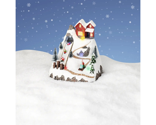 Dekorativt vinterlandskap med bergsstuga och pulkaåkare