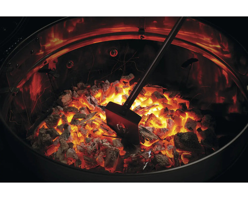 Glödande träkol med spade i kolgrillen