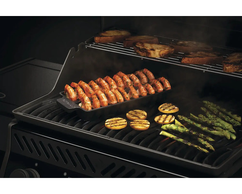 Grillade räkor i grillpanna med bröd, citron och sparris på en grill.