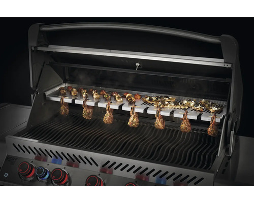 Grill i rostfritt stål med spett och grillad mat.