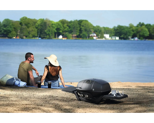 Scen med ett par vid sjön och en bärbar gasolgrill i förgrunden